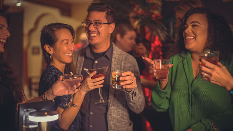 Three smiling people raise their cocktail glasses at the Magic Hideaway, inside Casa Monica Resort and Spa, St. Augustine