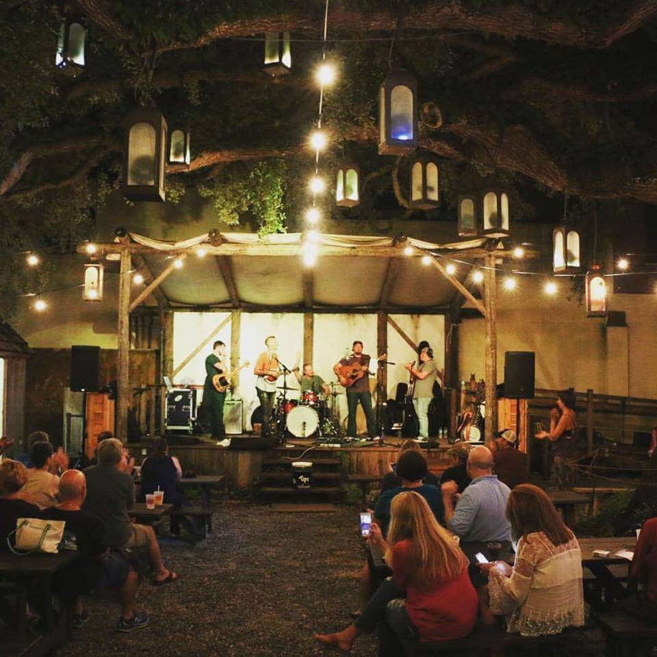 People watching a band on stage with laterns hanging from trees at night at Colonial Music Park, St. Augustine.