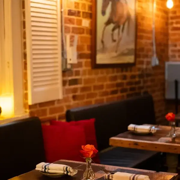 Dim lighting, brick wall, with black and red booth and tables set at Drunken Horse Restaurant St. Augustine.
