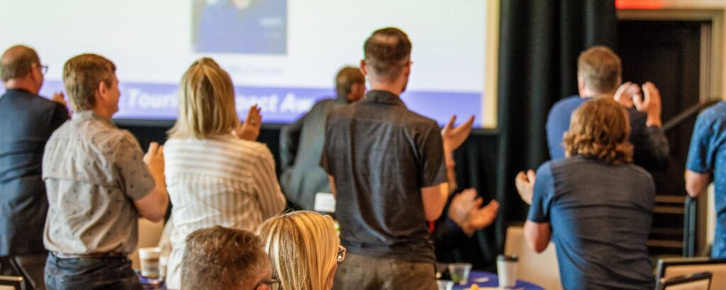 guests standing and clapping in conference room