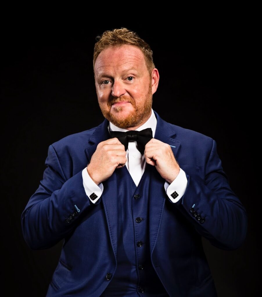Magician Bill Abbott displaying blue tuxedo and black bow tie