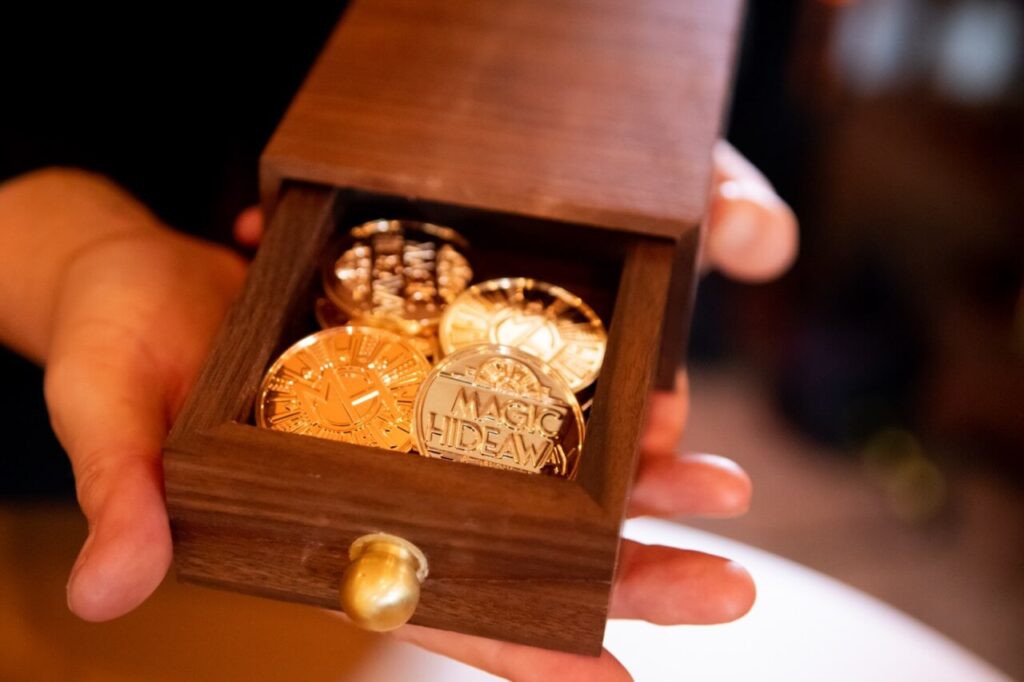 gold coins in wooden box being held by hands.