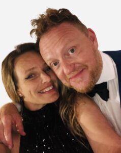 woman in black sequence dress and man in blue tuxedo smiling